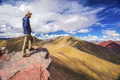 Top Tips for visiting rainbow mountain peru - Man standing on edge looking onto rainbow mountain